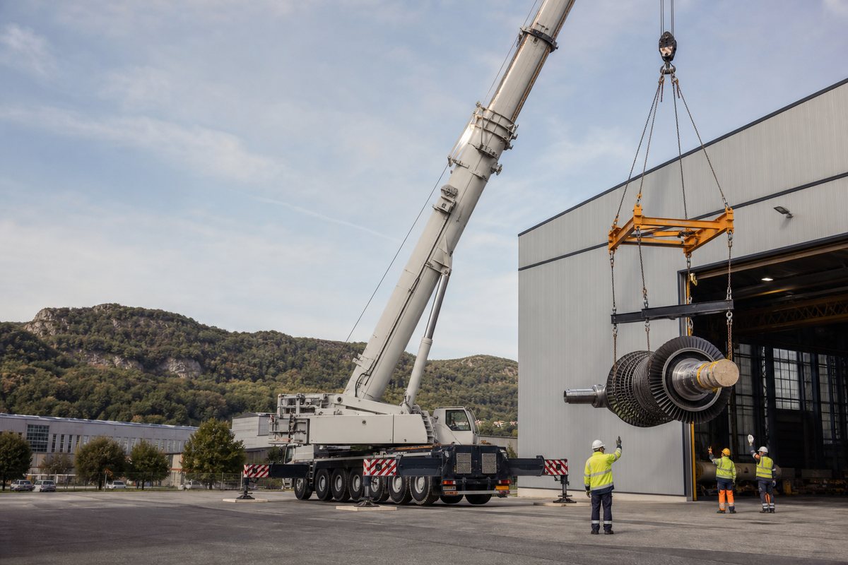 Mise en situation d’un grue mobile automotrice avec une équipe de levage pour levage de composant industriel, dans un environnement inspiré de Belfort